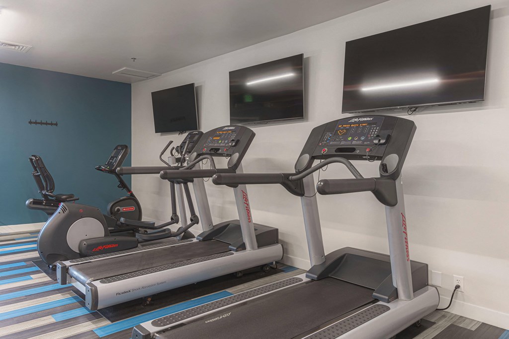two treadmills and two televisions in a gym room